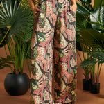 Woman standing with hands in pockets wearing printed palazzo pants.