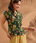 Woman wearing black tiki print camp collar blouse with lightweight linen blend fabric.