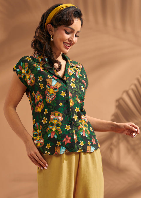 Woman wearing black tiki print camp collar blouse with lightweight linen blend fabric.