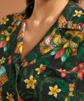 Close-up of camp collar and colorful tiki mask print on tropical blouse.