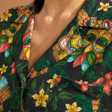 Close-up of camp collar and colorful tiki mask print on tropical blouse.