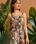 Woman wearing a floral tank top standing among tropical plants with a brown background
