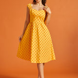 Woman wearing a yellow polka dot cotton fit and flare midi dress with sweetheart neckline and pockets.
