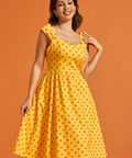 Woman wearing retro-inspired polka dot midi dress with sweetheart bodice and full skirt.
