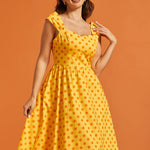 Woman wearing retro-inspired polka dot midi dress with sweetheart bodice and full skirt.