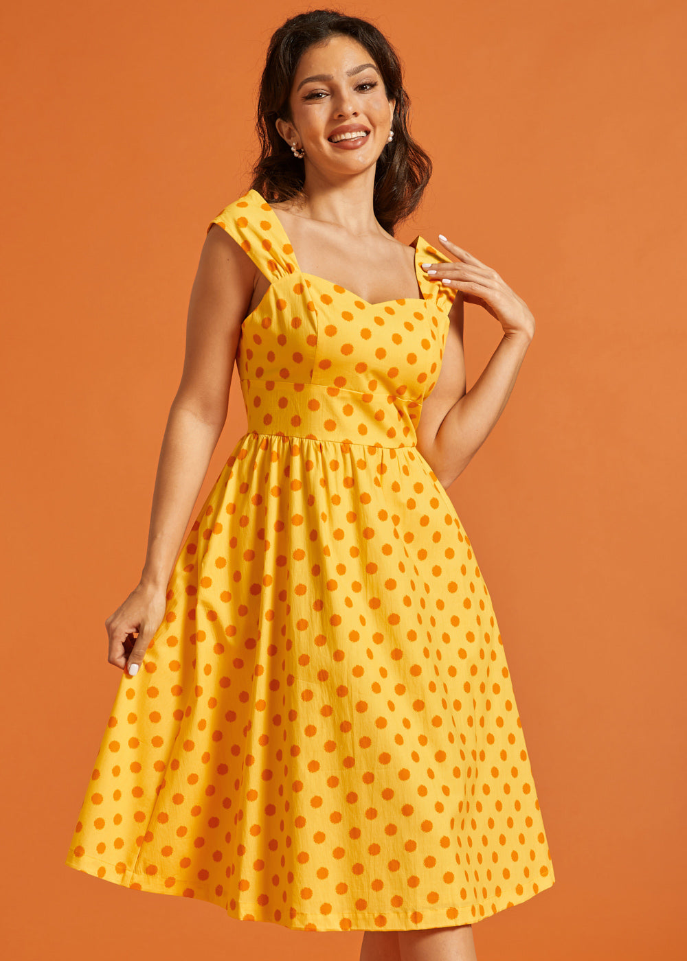 Woman wearing retro-inspired polka dot midi dress with sweetheart bodice and full skirt.