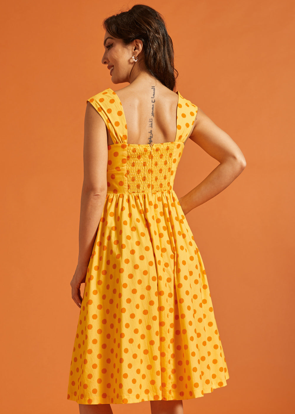 Back view of yellow fit and flare dress with stretchy smocked back and gathered skirt.