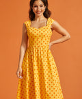 Woman wearing vintage-inspired yellow cotton midi dress with full skirt and side pockets.