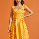 Woman wearing vintage-inspired yellow cotton midi dress with full skirt and side pockets.