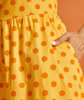 Detail of side pocket and painterly polka dot print on yellow cotton dress.