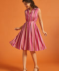 Woman wearing a pink striped sleeveless button-front midi dress with side pockets.