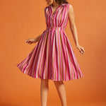 Woman wearing a pink striped sleeveless button-front midi dress with side pockets.