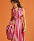 Woman wearing colorful striped sleeveless dress with full skirt and side pockets.