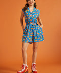Front view of a novelty roller skate print romper with a camp collar and pockets.