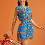 Woman wearing a blue roller skate print romper with a tie waist and cap sleeves.