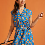 Front view of a blue novelty print romper with an adjustable tie belt.