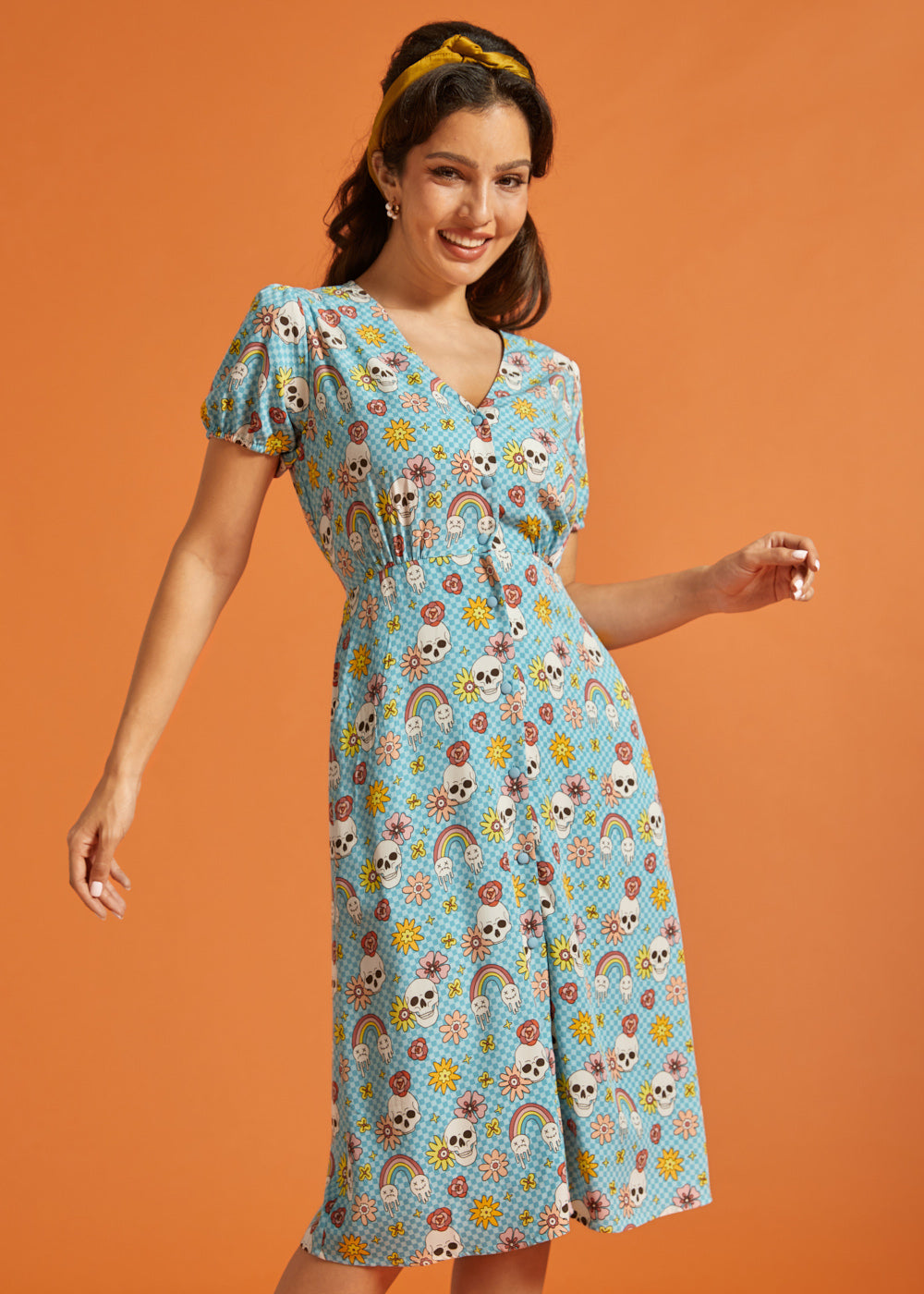 Woman wearing whimsical skull and floral print midi dress with tie waist.