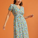Woman wearing whimsical skull and floral print midi dress with tie waist.