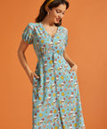 Woman modeling retro novelty print midi dress with functional front buttons and pockets.