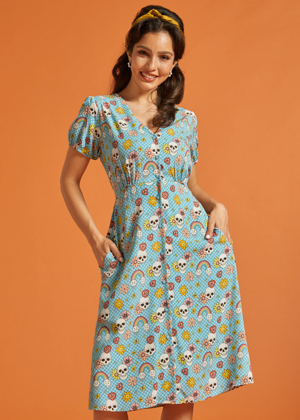 Woman wearing a blue novelty skull print button-front midi dress with puff sleeves and pockets.