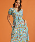 Woman wearing a blue novelty skull print button-front midi dress with puff sleeves and pockets.