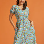 Woman wearing a blue novelty skull print button-front midi dress with puff sleeves and pockets.