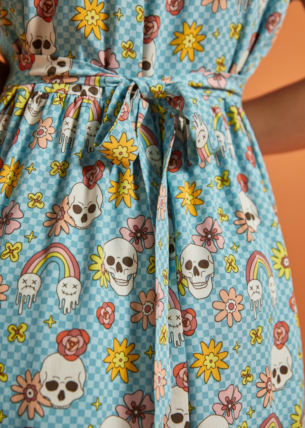 Close-up of attached self-tie waist on blue novelty skull and floral print dress.