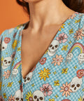 Close-up of V-neckline featuring checkerboard novelty print with skulls, flowers and melting rainbows.