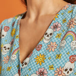 Close-up of V-neckline featuring checkerboard novelty print with skulls, flowers and melting rainbows.