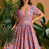 Woman wearing tropical novelty print midi dress with button-front bodice and full skirt.