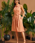 Woman wearing a vintage-inspired button-front linen shirt dress with pockets.