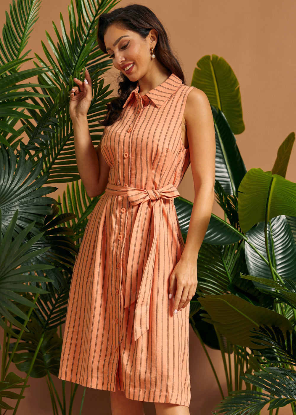 Woman wearing a peach pinstriped midi shirt dress with a waist tie.
