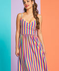 Woman wearing rainbow stripe sleeveless midi dress with surplice neckline and pockets