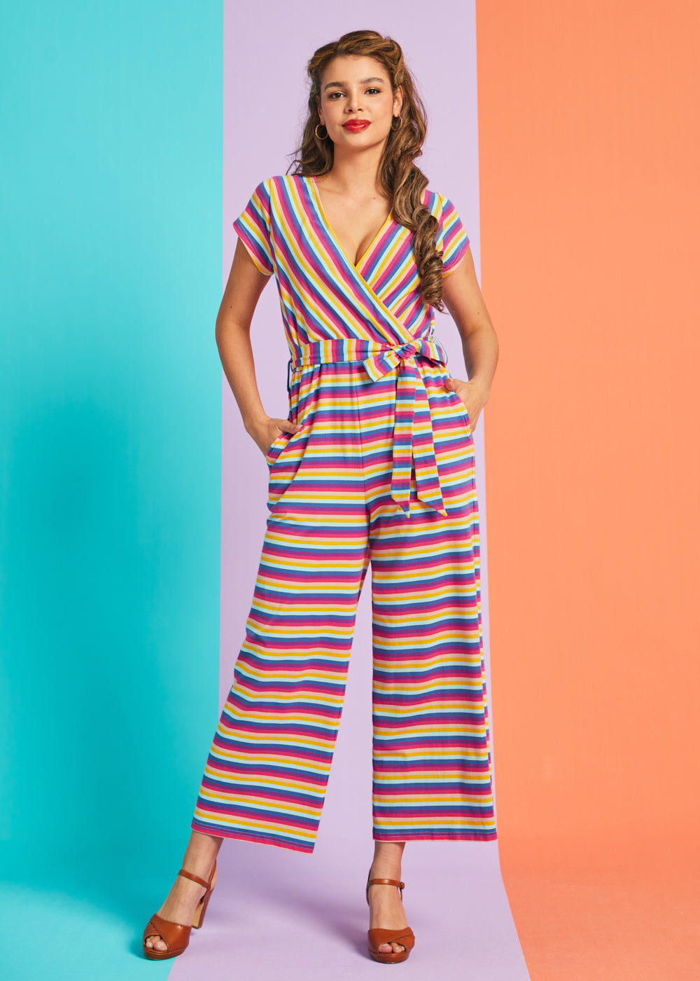 Model posing in rainbow stripe cropped wide-leg jumpsuit with pockets and adjustable waist tie
