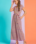 Woman wearing a colorful striped jumpsuit on a two-tone blue and orange background