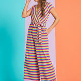 Woman wearing a colorful striped jumpsuit on a two-tone blue and orange background