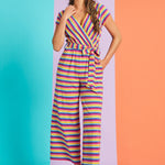 Model wearing retro-inspired rainbow stripe jumpsuit with tie waist and wide legs
