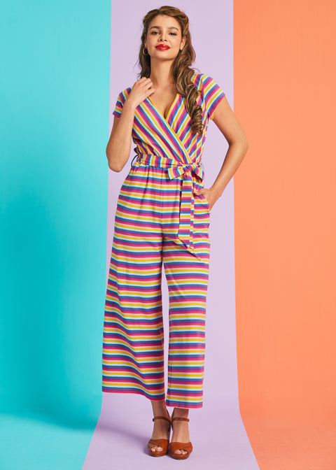 Model wearing retro-inspired rainbow stripe jumpsuit with tie waist and wide legs