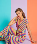 Model sitting in rainbow stripe faux-wrap jumpsuit with cropped wide-leg silhouette