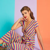 Model sitting in rainbow stripe faux-wrap jumpsuit with cropped wide-leg silhouette