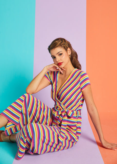 Model sitting in rainbow stripe faux-wrap jumpsuit with cropped wide-leg silhouette