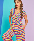 Model wearing rainbow stripe faux-wrap wide-leg jumpsuit with tie waist and pockets in Boardwalk Taffy