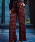 Woman wearing red tartan plaid wide leg pants with a black sash belt and side pockets, styled with a black long sleeve top