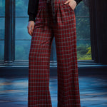 Woman wearing red tartan plaid wide leg pants with a black sash belt and side pockets, styled with a black long sleeve top