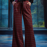 Woman wearing red tartan plaid wide leg pants with hands in the side pockets, showing the removable black bow sash belt