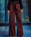 Front view of red tartan plaid wide leg pants showing the high waist, front pleats, black sash belt, and full-length legs