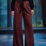 Front view of red tartan plaid wide leg pants showing the high waist, front pleats, black sash belt, and full-length legs