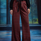 Front view of red tartan plaid wide leg pants showing the high waist, front pleats, black sash belt, and full-length legs