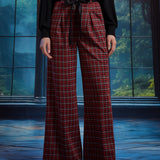 Front view of woman wearing red tartan plaid wide leg pants with black sash belt, showing the pleated waist and wide-leg fit