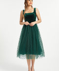 Full-length studio view of emerald green velvet dress with layered polka dot tulle skirt